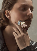 Woman wearing a stack of colorful rings with a neutral background