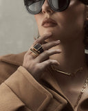 Close-up of a person wearing a gold ring with a dark stone.