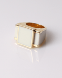 Gold ring with a rectangular white stone on a light gray background