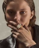 Person wearing a gold ring with a neutral background