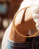 Gold bracelet on a wrist with a blurred background