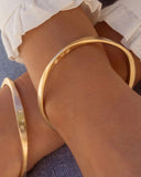 Gold bangles on a wrist with a blurred background