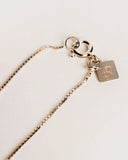 Silver necklace with a tag on a light background