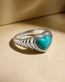 Silver ring with a turquoise heart-shaped stone on a beige background