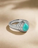 Silver ring with a turquoise stone on a beige background