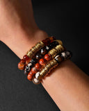 Stack of beaded bracelets on a wrist against a dark background