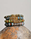 Stack of colorful artisan beaded bracelets on a textured stone surface with a neutral background