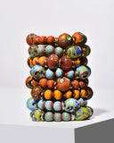 Stack of colorful artisan beaded bracelets on a white background