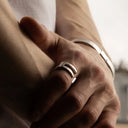 Close-up of a man's hand wearing a silver ring and bracelet.