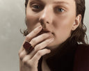Woman wearing a large ring on her finger against a neutral background