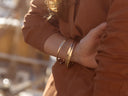 Close-up of a person wearing gold bracelets on a blurred background