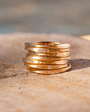 Stack of gold rings with embedded diamonds on a textured surface