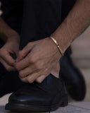 Man wearing a gold bangle with a blurred background
