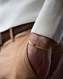 Close-up of a person wearing a gold bracelet on a blurred background