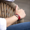 Person wearing a red leather wrap bracelet on a blurred background