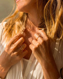 Close-up of a woman wearing gold rings on a blurred natural background