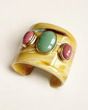 Wide gold natural horn cuff bracelet with colorful stones on a light background