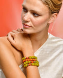 Woman wearing a colorful beaded bracelet on a plain background