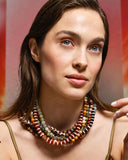 Woman wearing a colorful layered beaded necklaces against a blurred background