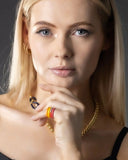 Woman wearing a colorful stack of enamel rings against a neutral background