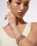 Woman wearing a silver bangle bracelet on a plain background