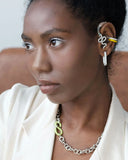 Woman wearing a white top with a close-up of her earring, ear cuffs and necklace.