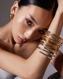 Woman wearing gold and silver bangles on a neutral background