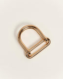 A polished gold metal ring with a double-bar design, shown on a clean, light off-white background.