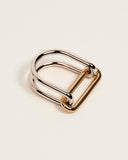 A two-tone metal ring with polished silver-toned loops and a gold-toned frame, photographed on a clean off-white background.