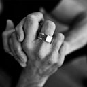 Close-up of a man wearing a silver ring with a square design.